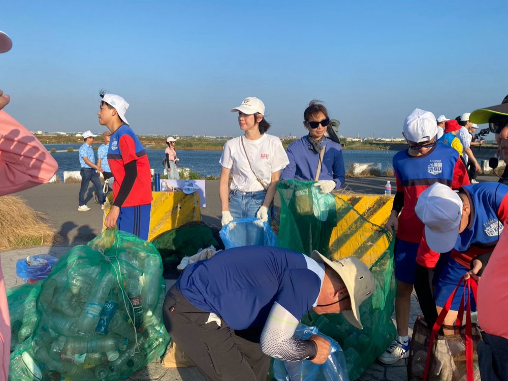 Volunteers tying up full mesh bags of collected plastic bottles