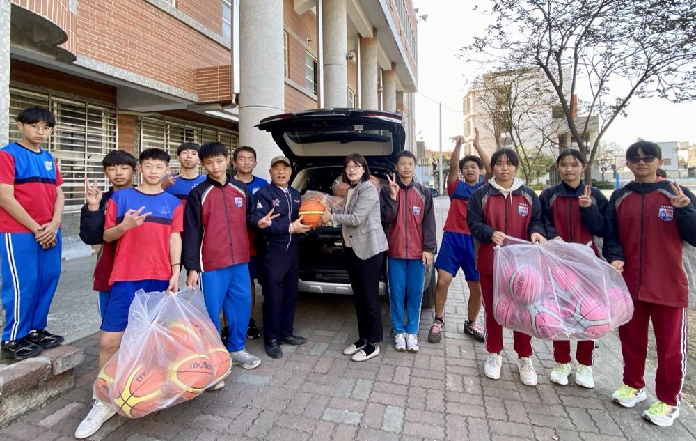 Zuoyi Co. representative handing over a basketball donation beside a car full of balls