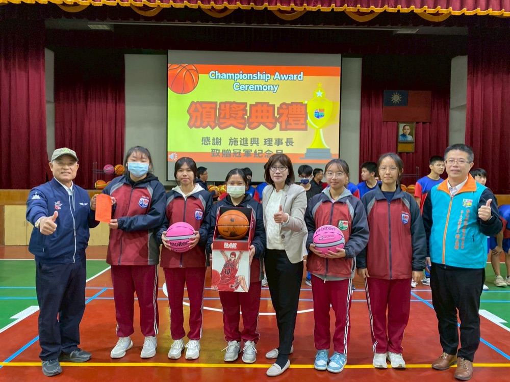 Winning girls' team members holding their trophies and commemorative basketballs