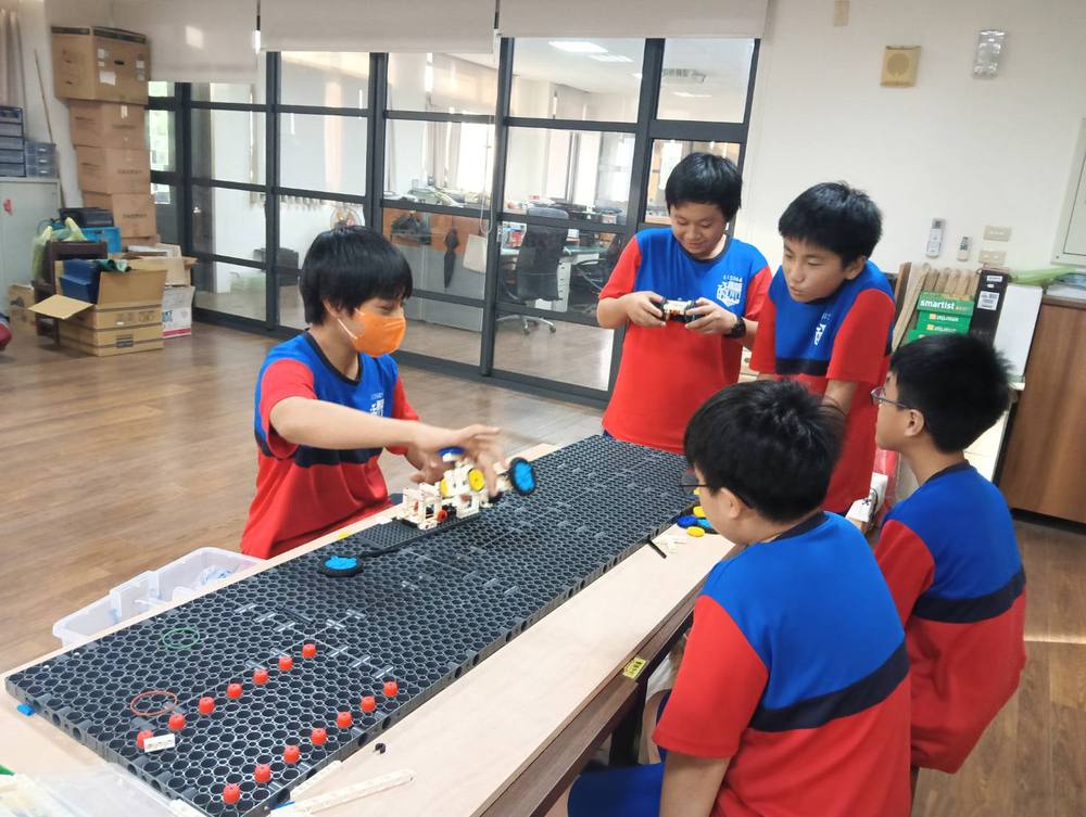 Students build a moving model on a black pegboard at the club table