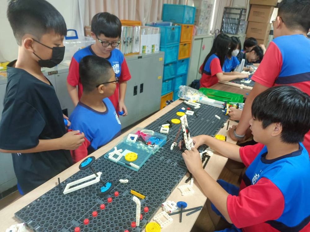 Students fit plastic parts together to build a mechanism