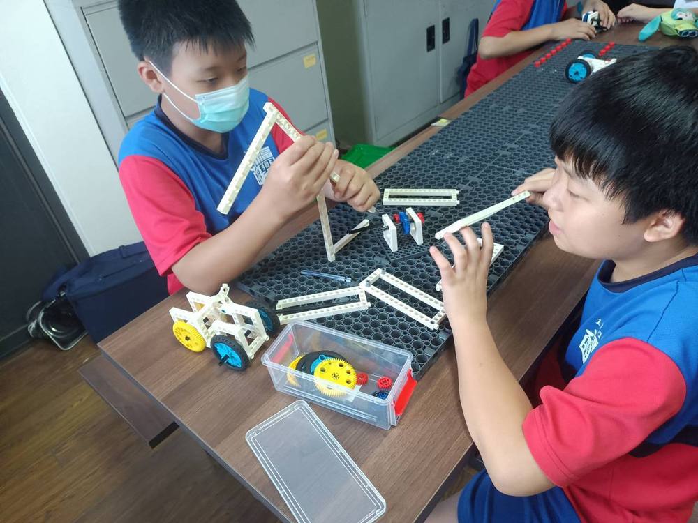 A student adjusts a model with wheels on the pegboard