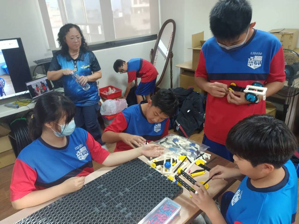 The club teacher guides a group of students working on their models