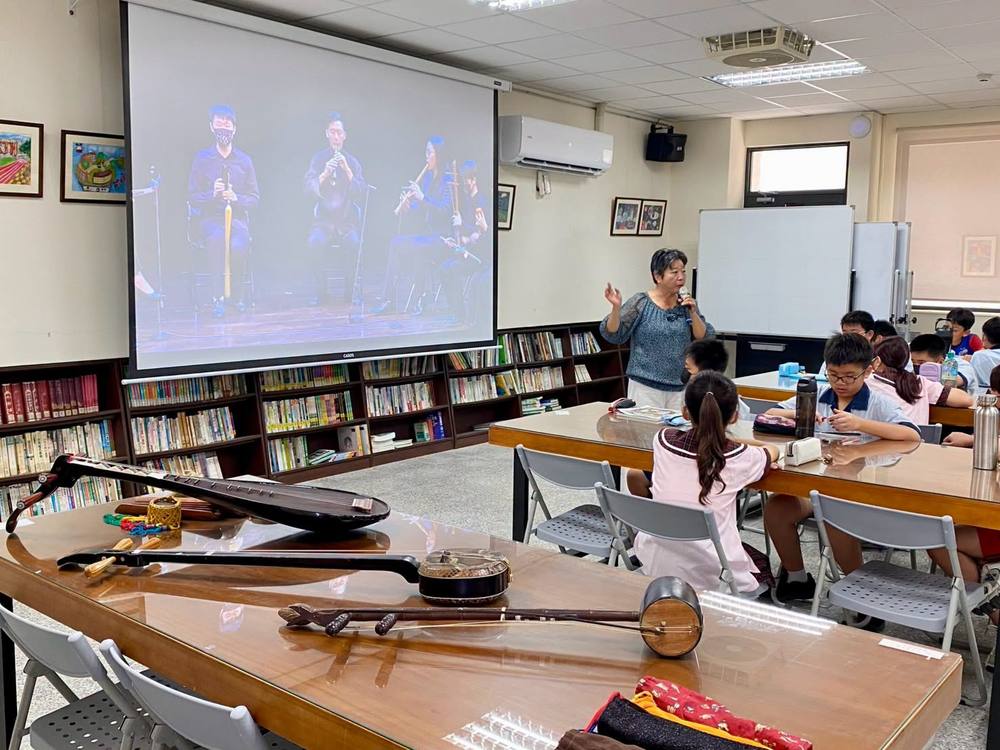 Nanguan instruments, including a pipa and a sanxian, laid out on a table in front of the class