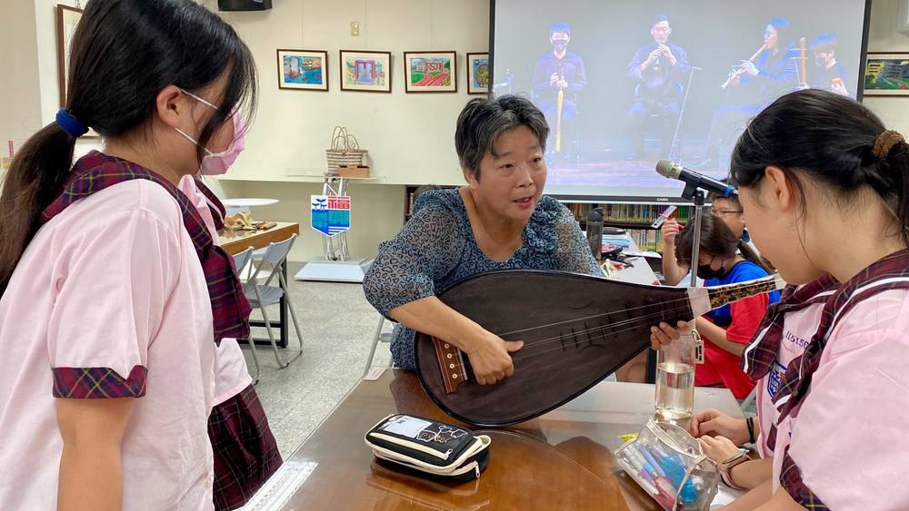 Students lean in as Teacher Wu shows them how to play the pipa