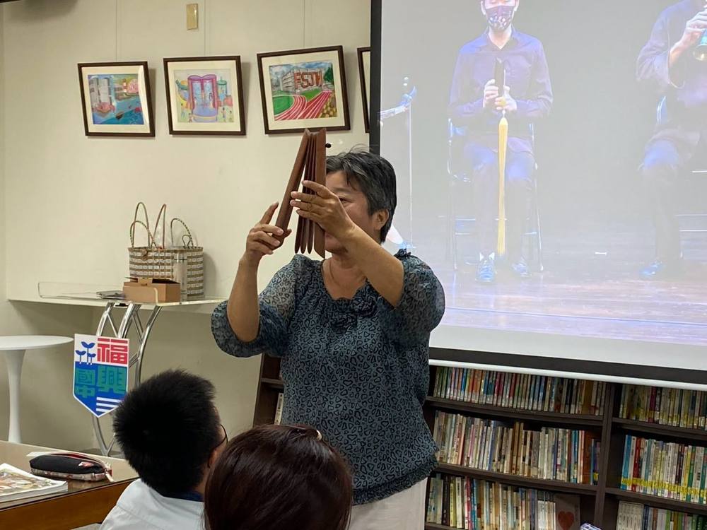 Teacher Wu holds up the pai, a set of wooden clappers that keeps the beat