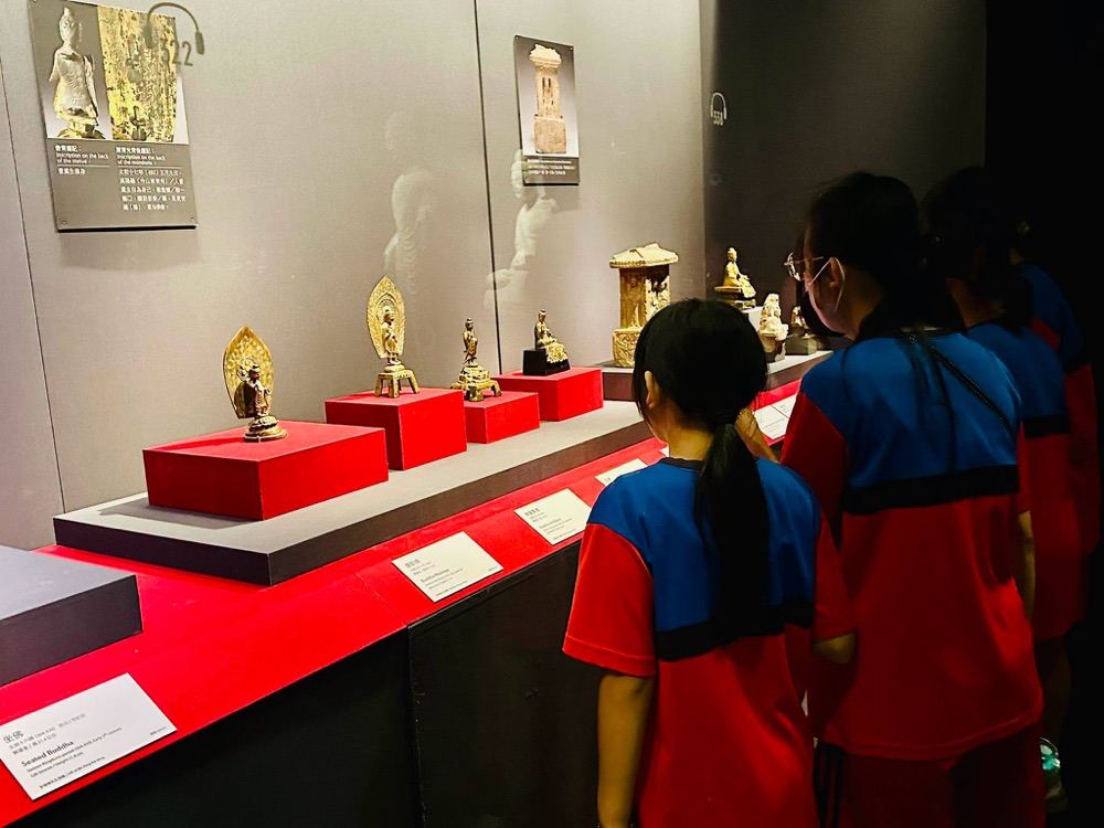 Two students standing close to a display case of artifacts