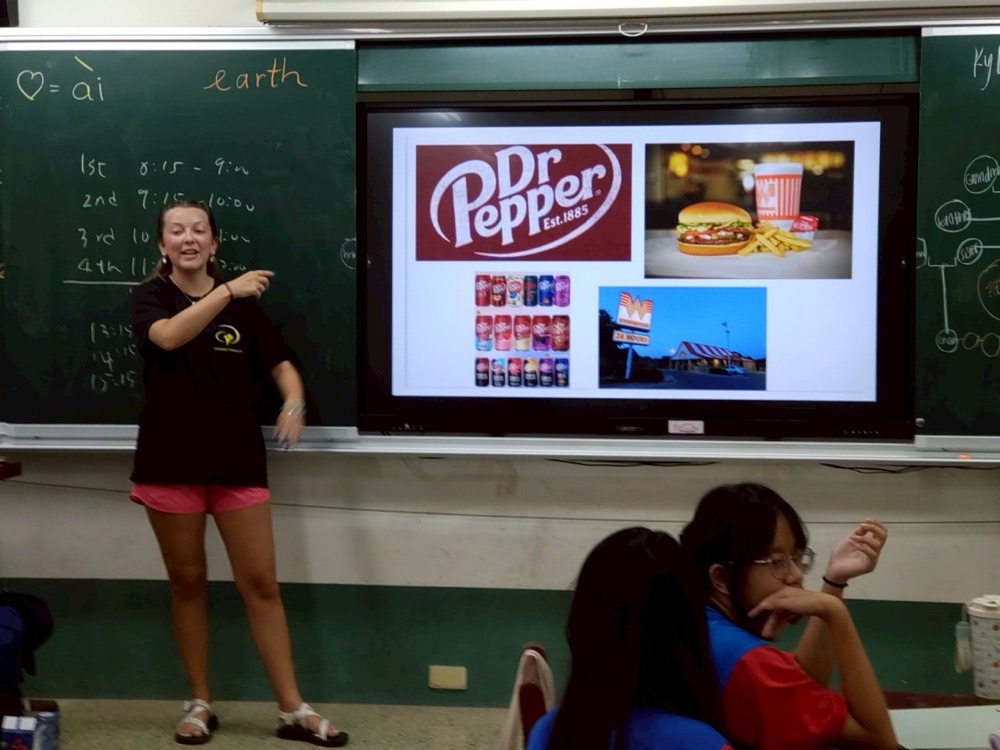 A foreign teacher presenting a slide about American culture, including Dr Pepper