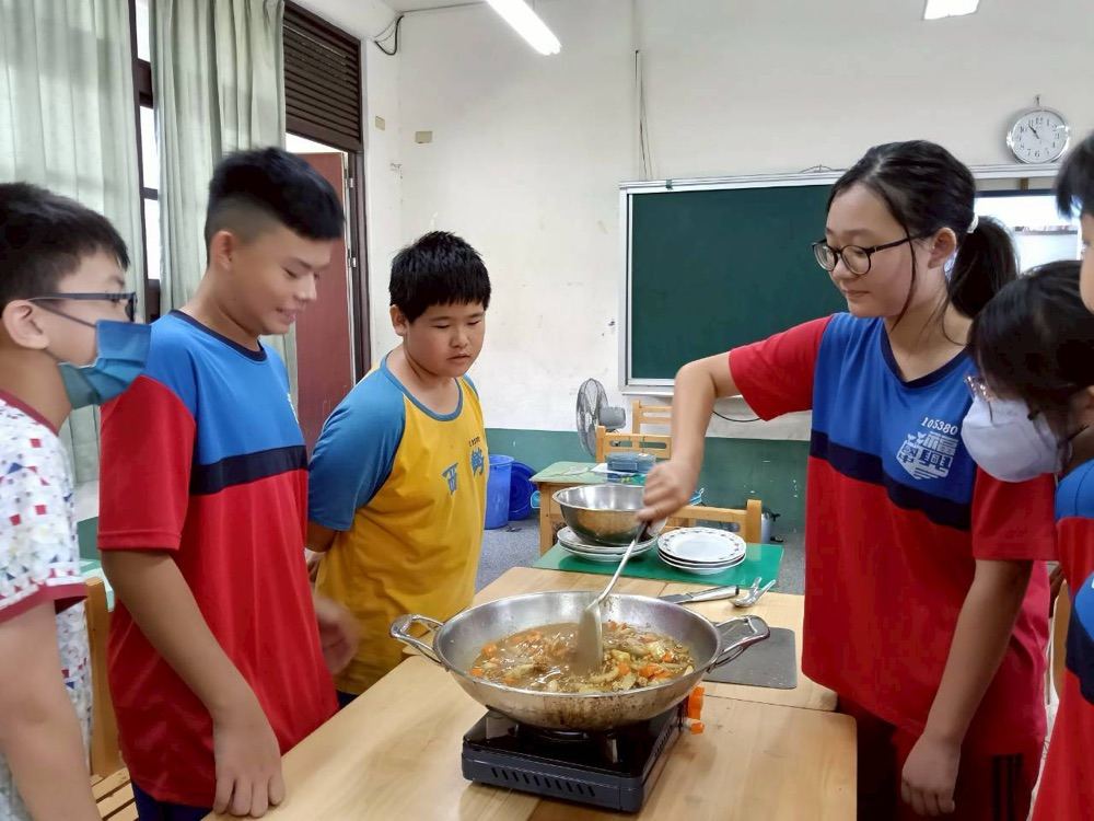 Students stirring a pot of stew together on a portable stove