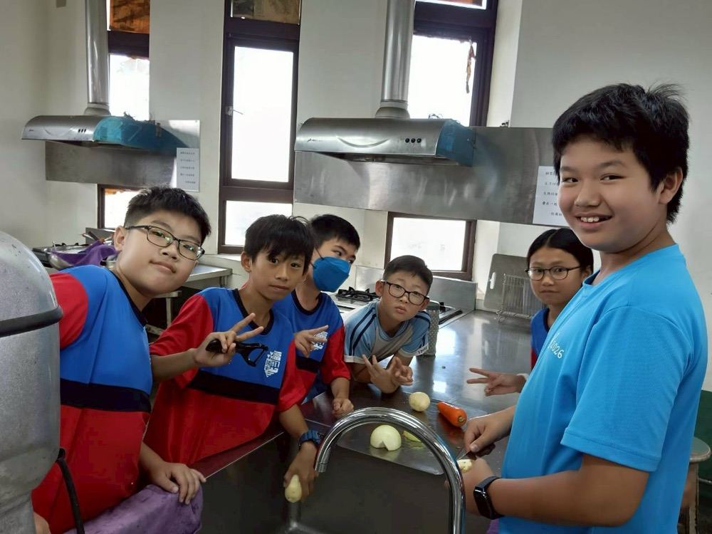 Students gathered around a kitchen counter preparing vegetables