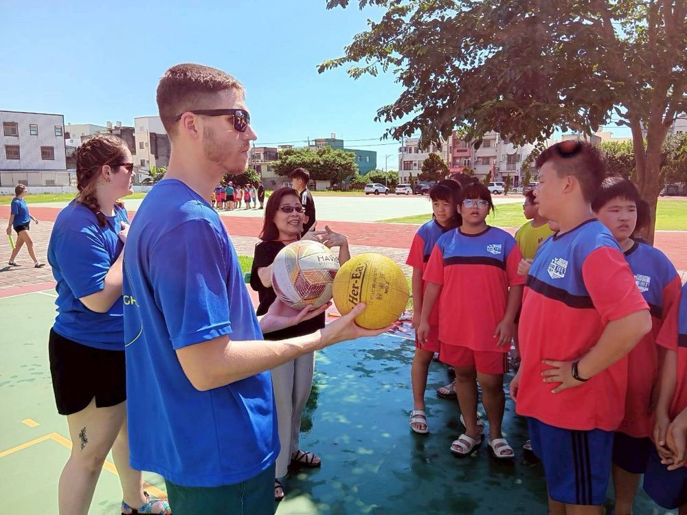 A foreign teacher explaining the rules of an outdoor ball game to students