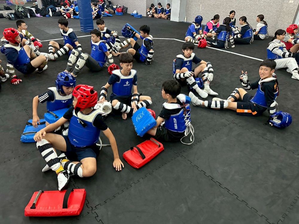 Students in sparring gear taking a break during training