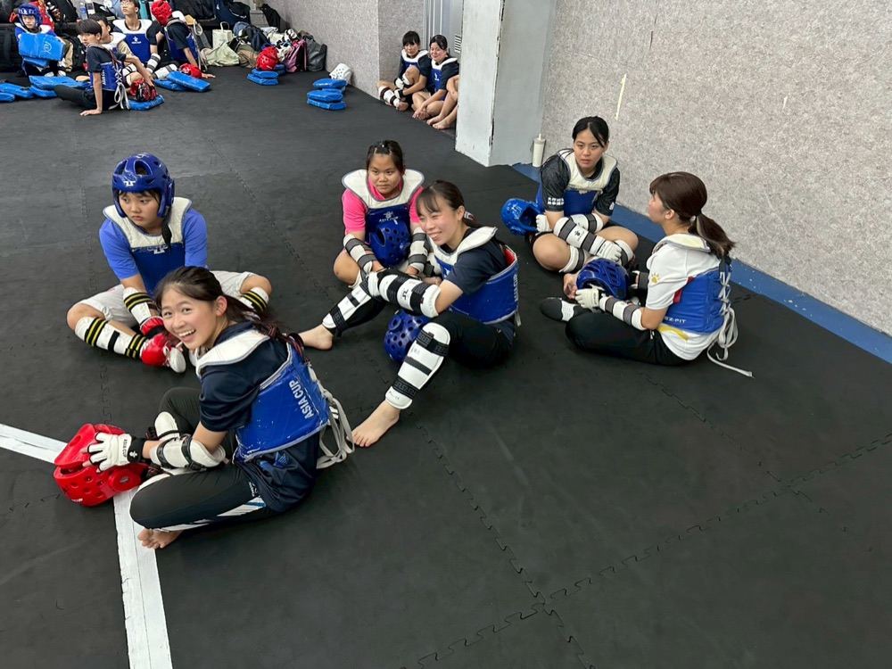 Students in protective gear chatting together on the training mat
