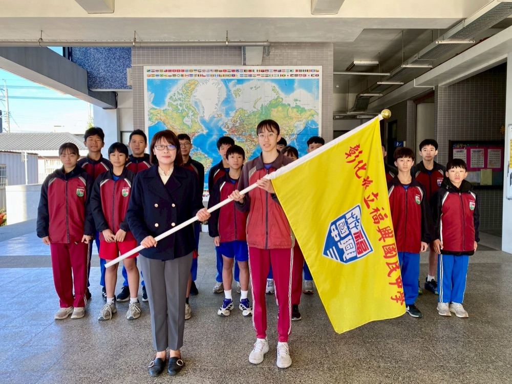A team member holding the school flag with the principal before a trip