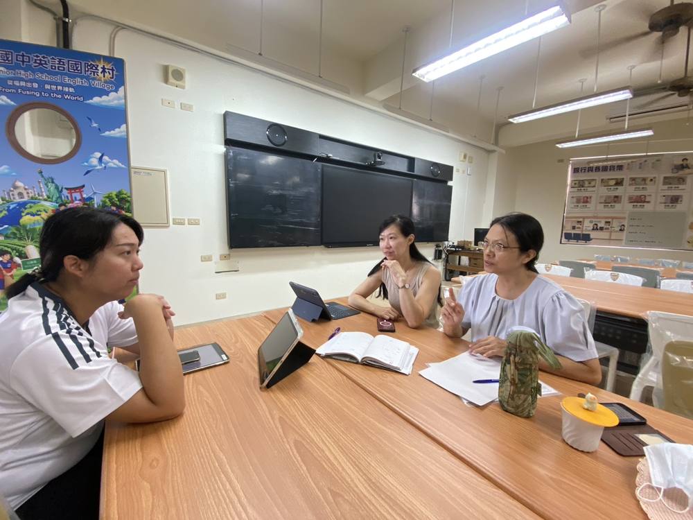 Fusing teachers sit at a table with tablets during the video planning meeting with Japan