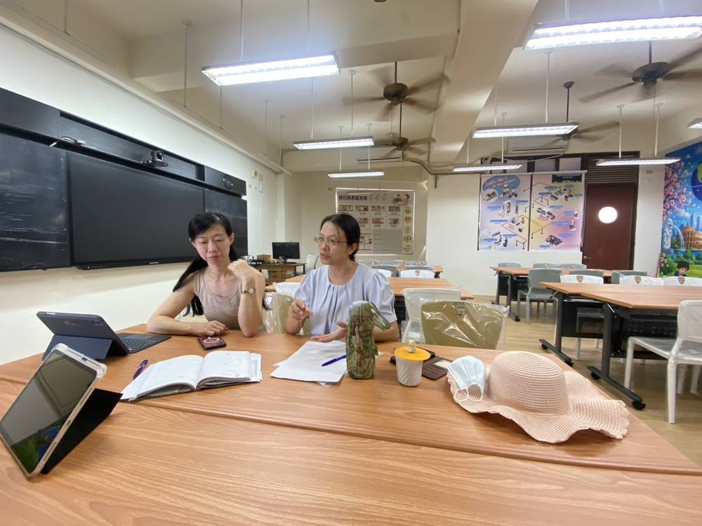 Teachers discuss the exchange program around a table in the English classroom
