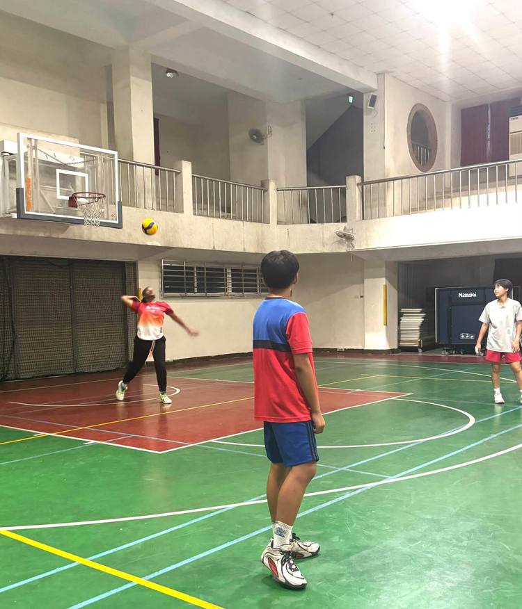 A student watches as Teacher Z sends the ball across the court