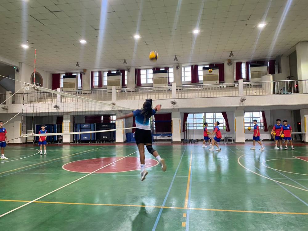 Teacher Z jumps for a spike at the volleyball net