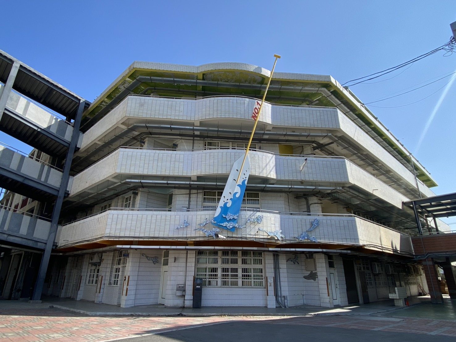 A curved façade decorated with an ocean-wave art banner · 海洋意象立面