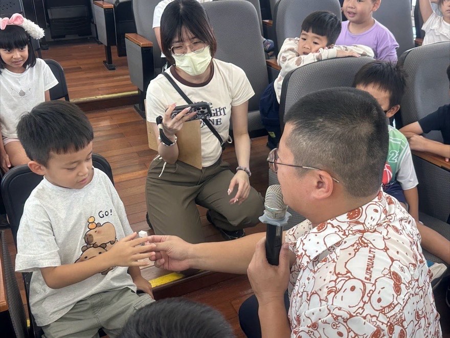 演員拿著麥克風走進觀眾席，與一位小朋友面對面互動
