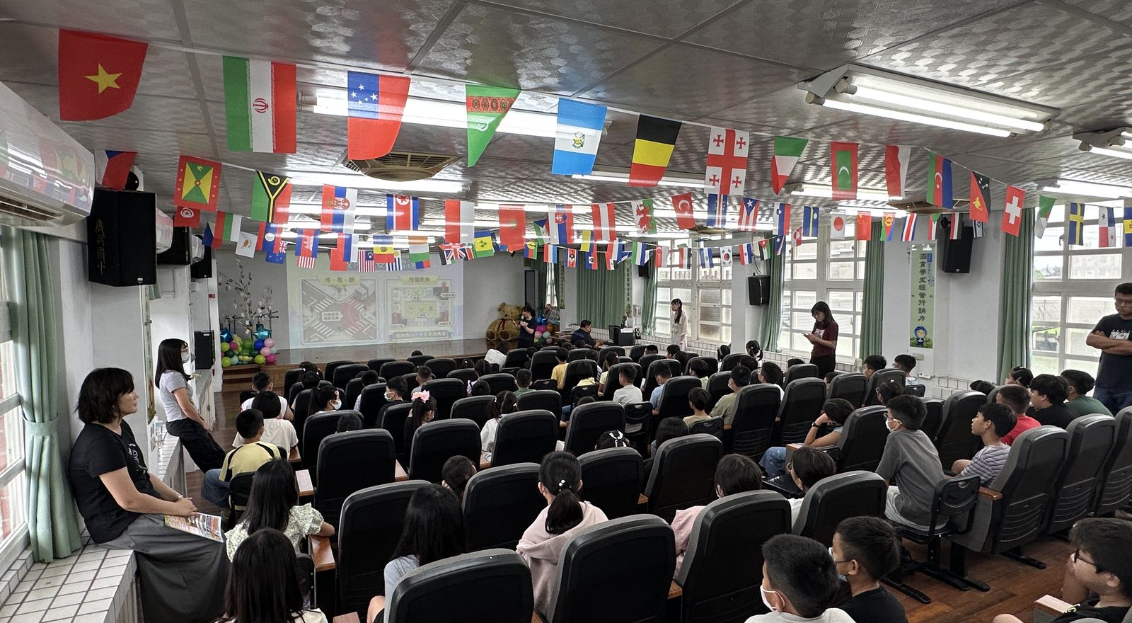 廣興國小活動中心懸掛各國國旗,全校學生集合參加友善校園宣導