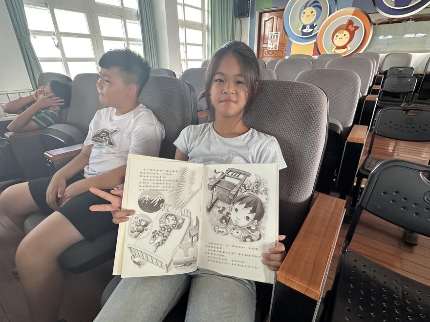 學生坐在座位上，展開故事繪本給大家看