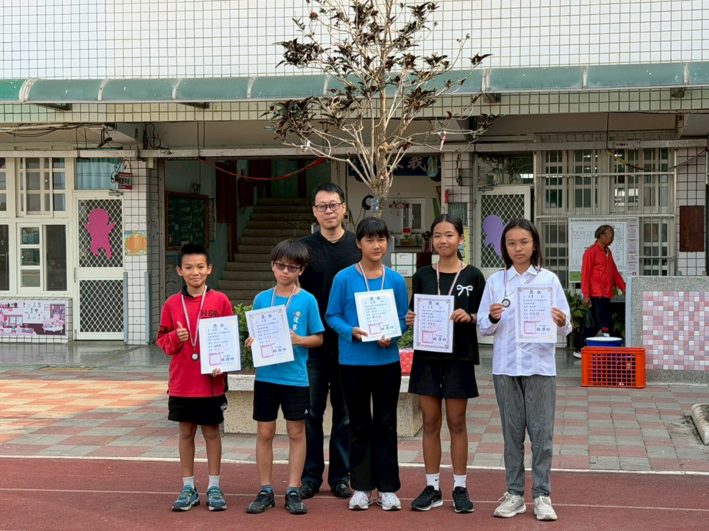 Students with award certificates outside the school's main building