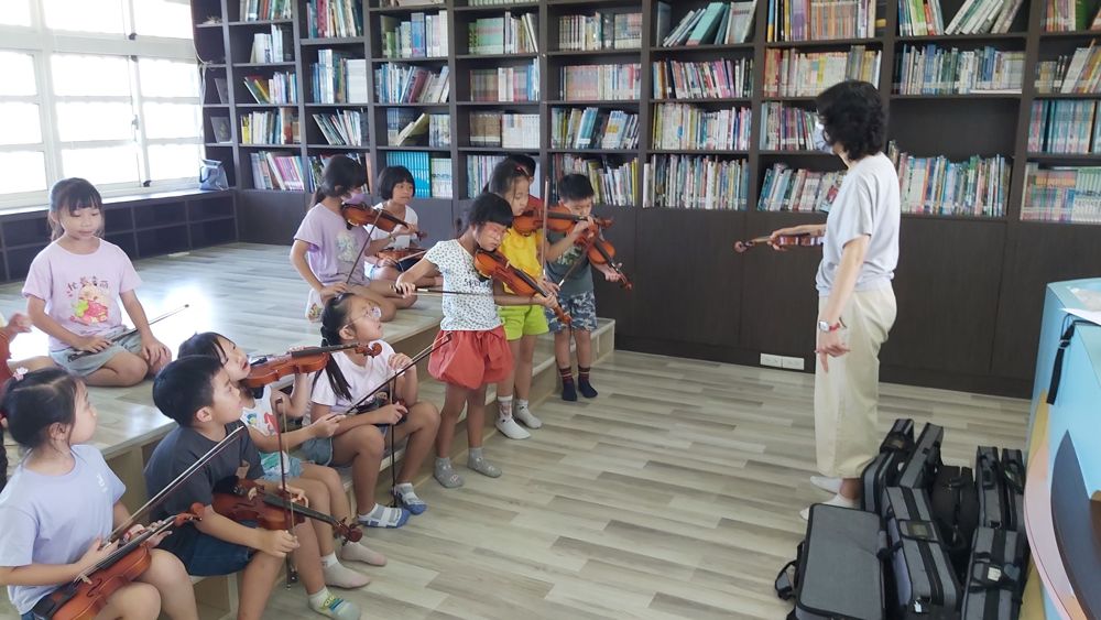 Beginner violin students seated in the school library