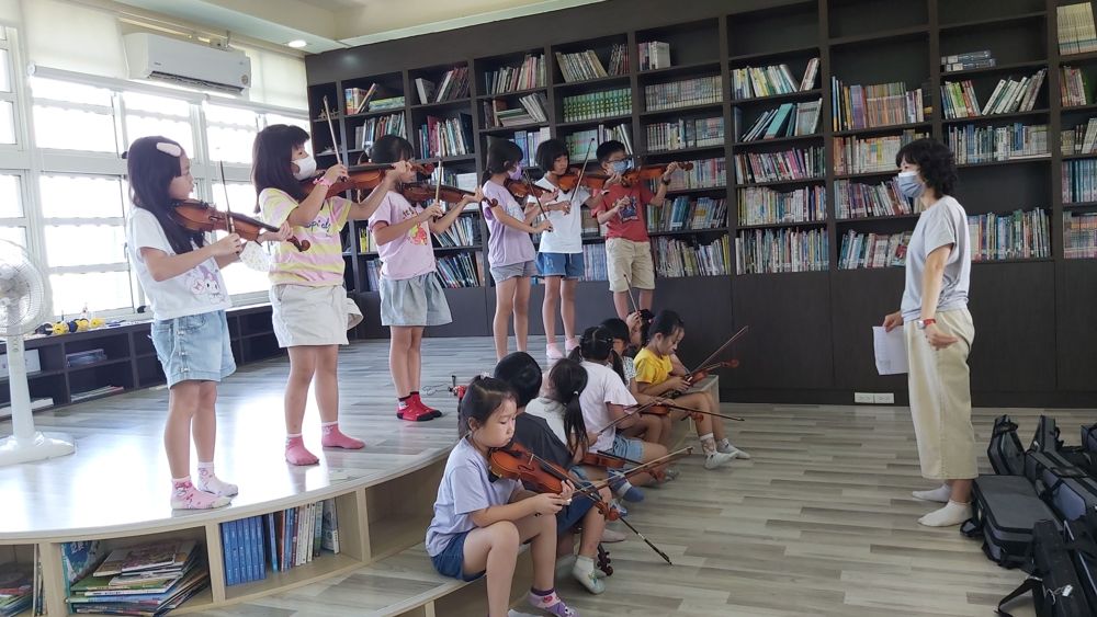A teacher guiding a young violin beginner