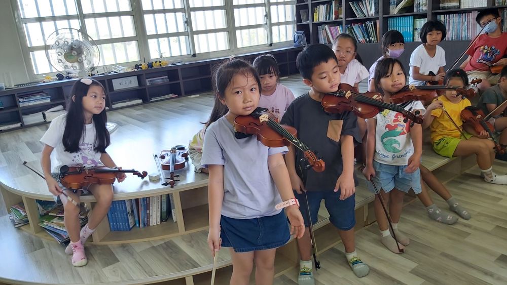 Children learning to hold the violin bow