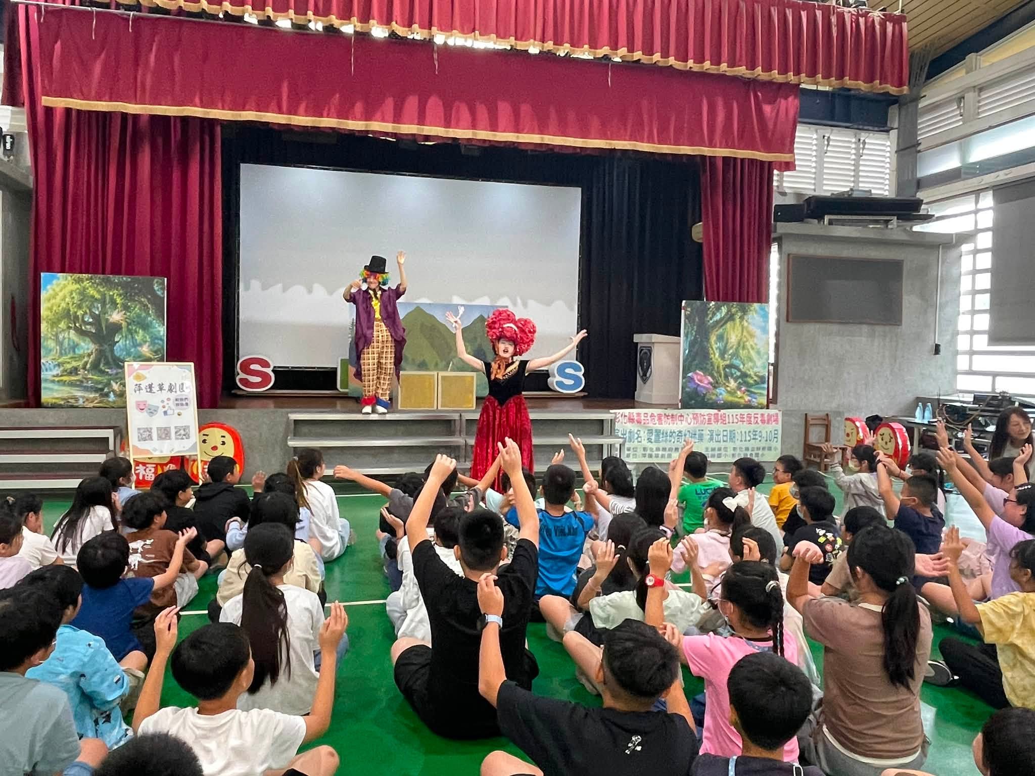 紅心皇后與瘋帽客在舞台上演出，學生舉手回應