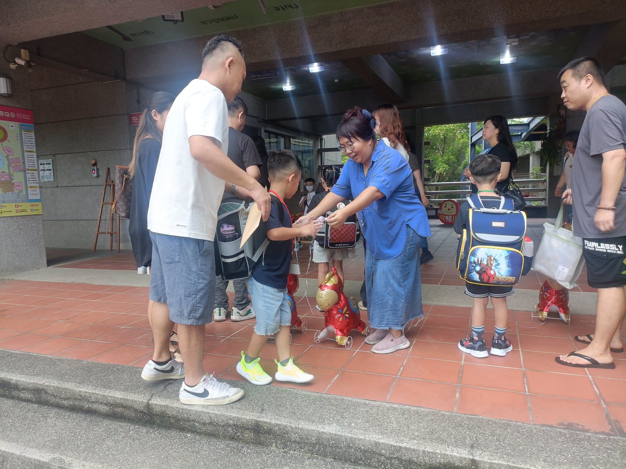 老師在校門口將「福氣小馬」氣球交給新生