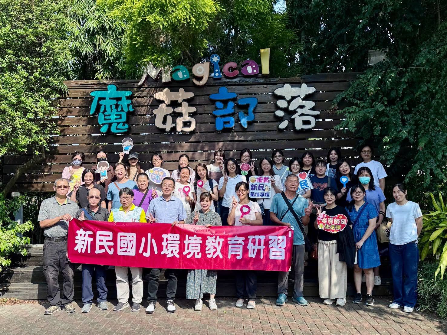 新民國小全體教職員手持「新民國小環境教育研習」布條，在魔菇部落入口合影