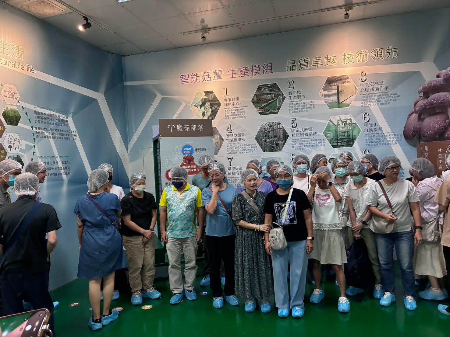 戴著髮帽、套著鞋套的新民教職員，在智能菇蕈生產模組展示牆前聆聽介紹
