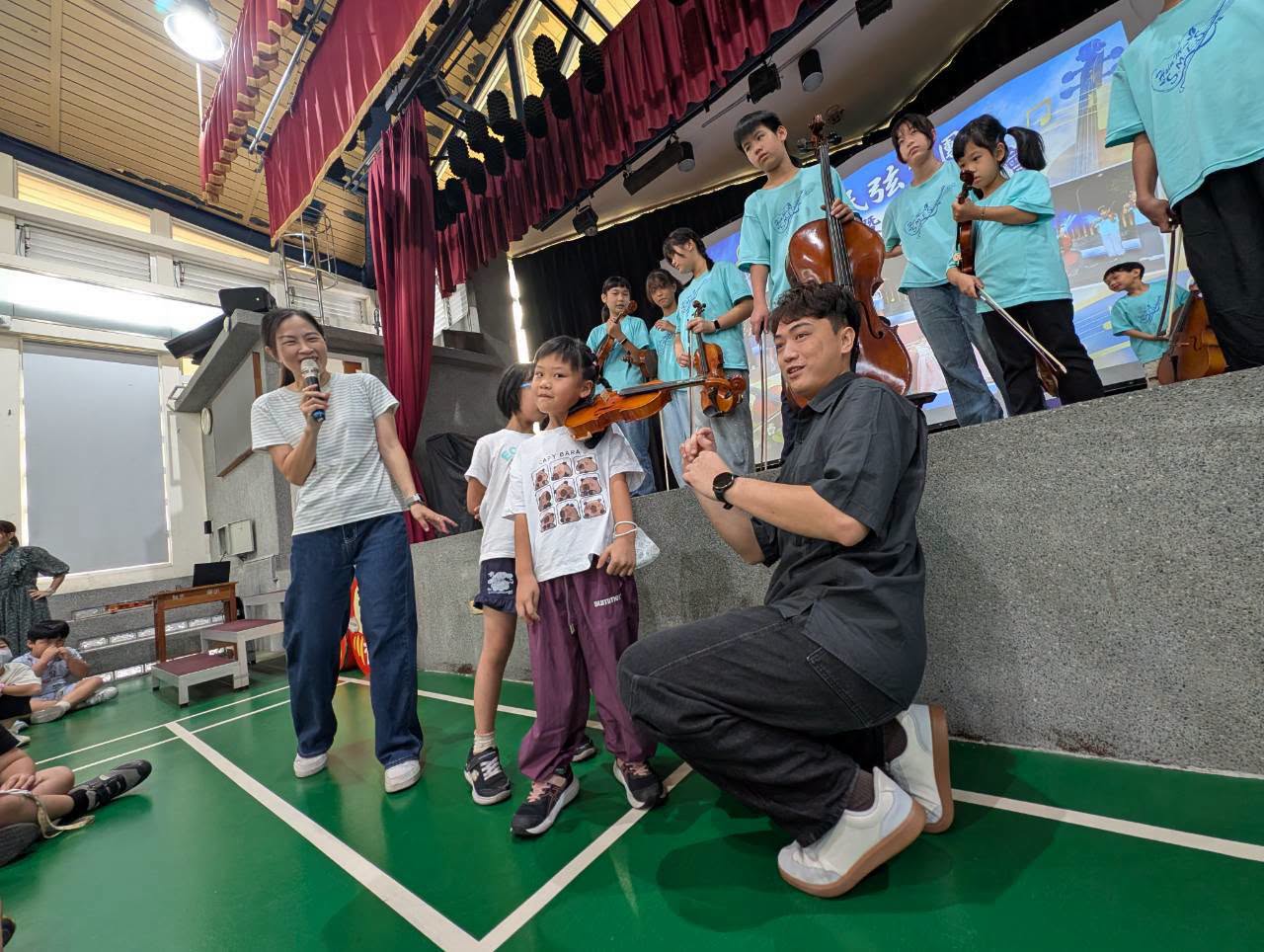 小朋友上台體驗夾琴姿勢，老師在一旁指導