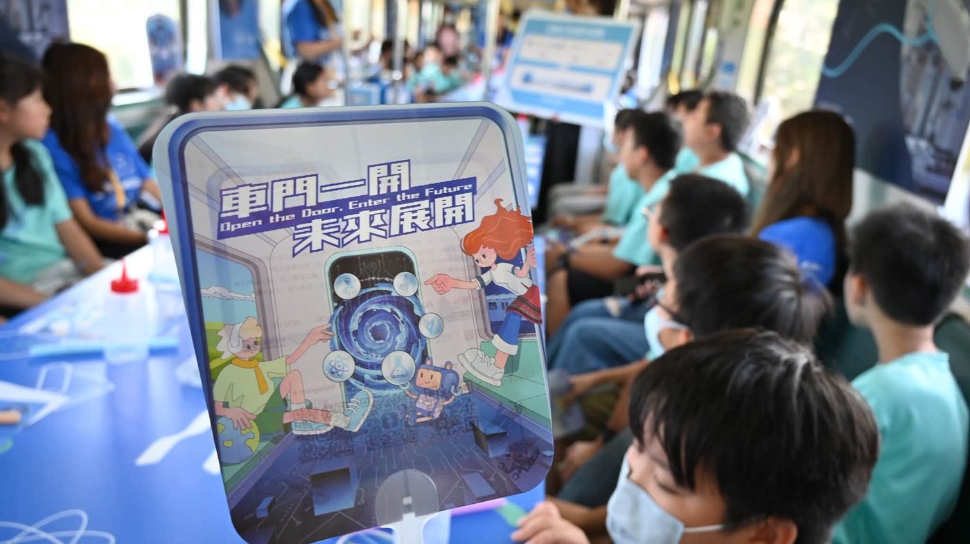 學生在車廂裡拿著「車門一開，未來展開」看板