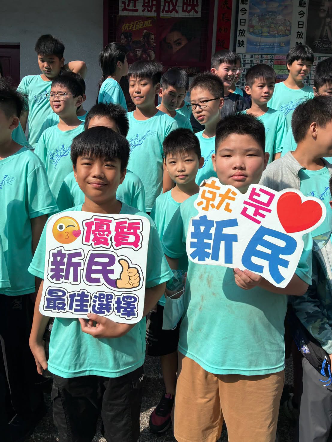 學生拿著「優質新民最佳選擇」「就是愛新民」手舉牌合影