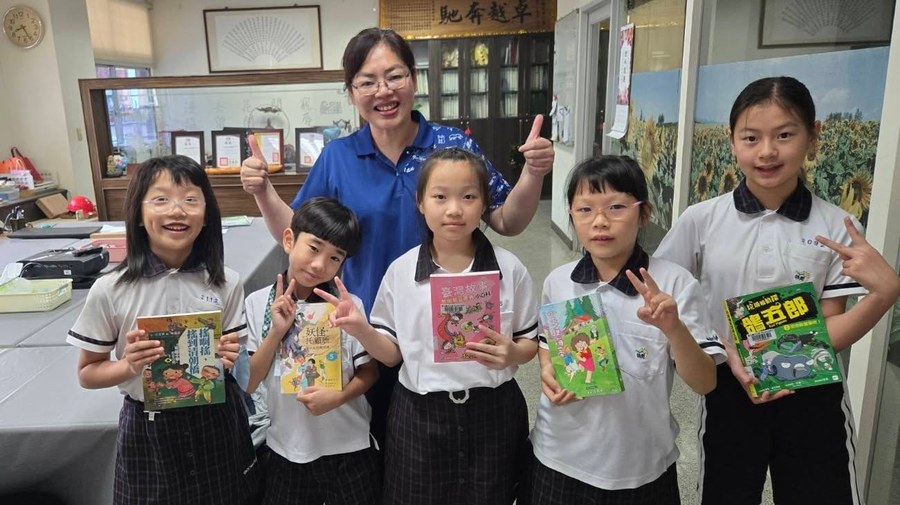 Principal Wang Hsin-Yi with students holding books 王心怡校長與學生