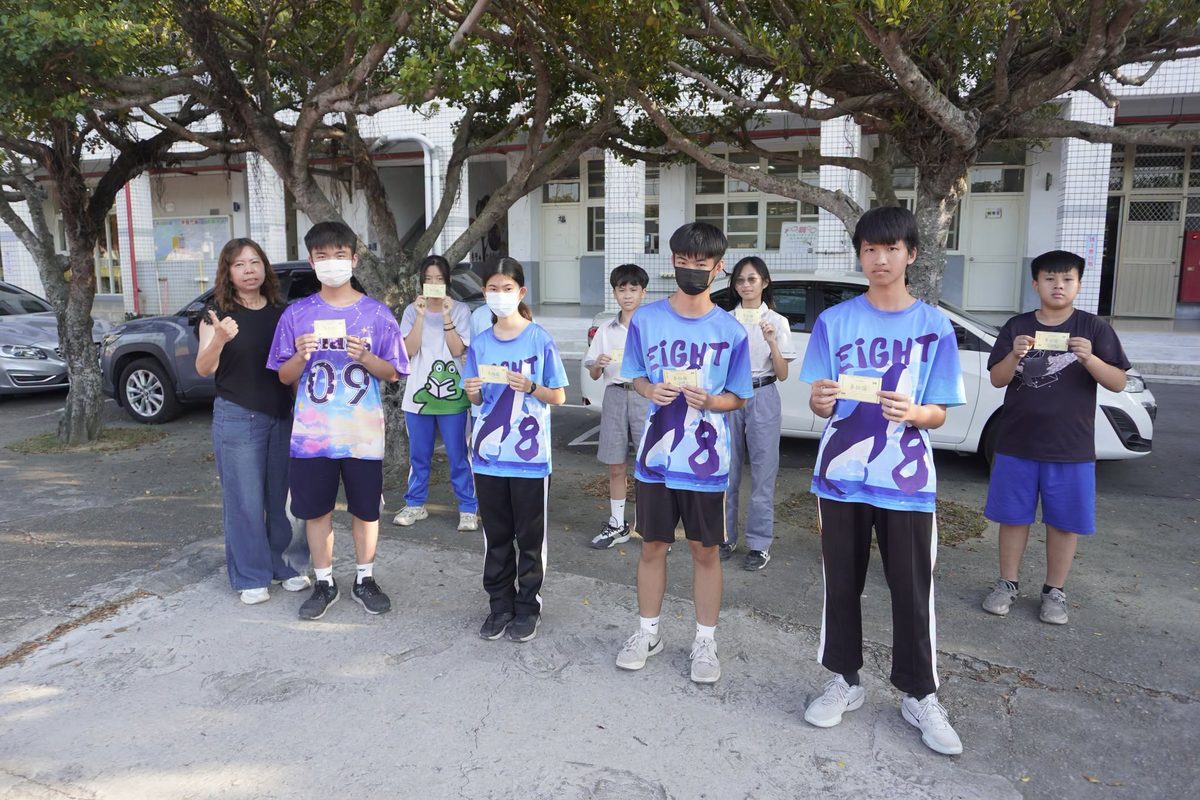 得獎的秀水國中同學在校園樹下手拿獎品，和老師一起合照 The winning Hsiushui students holding their prizes under the campus trees, with a teacher