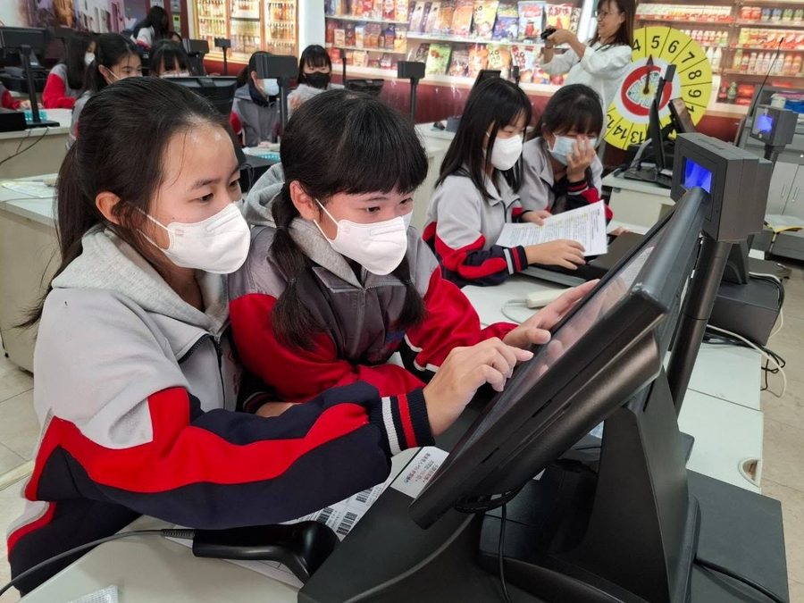 秀水國中學生在模擬商店裡操作收銀機觸控螢幕 Hsiushui students using a touchscreen cash register in a practice store