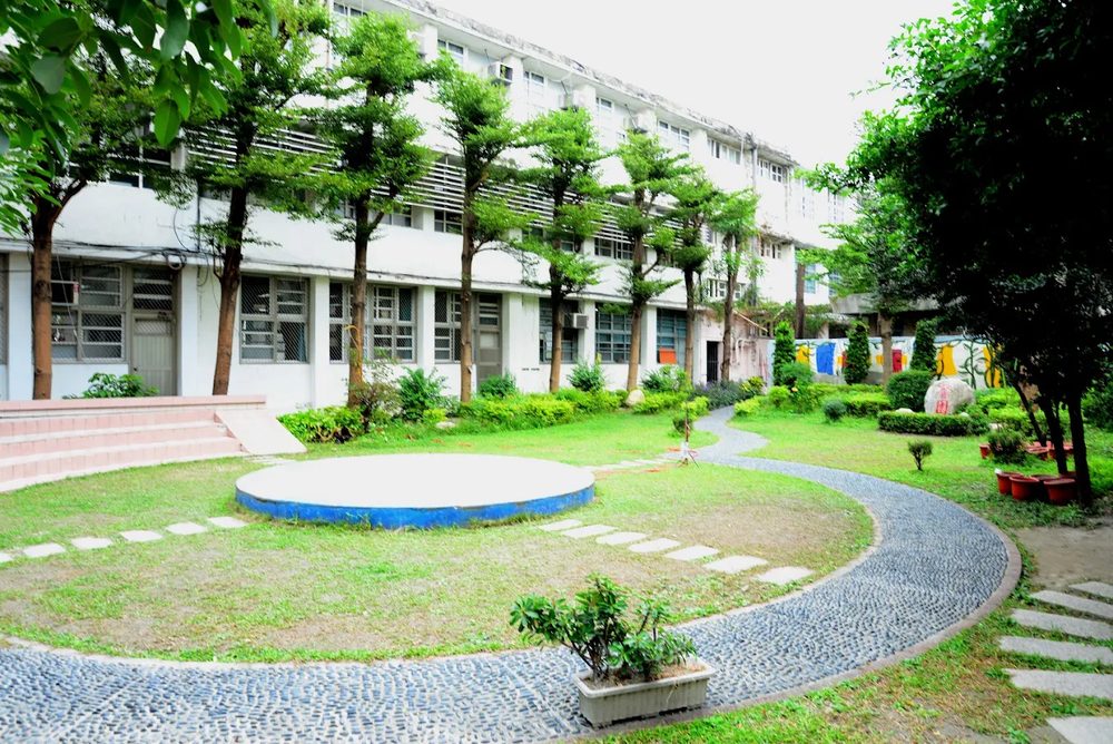 秀水國中中庭花園，有圓形平台、石頭步道與樹木 The Hsiushui courtyard garden, with a round platform, a pebble path and trees