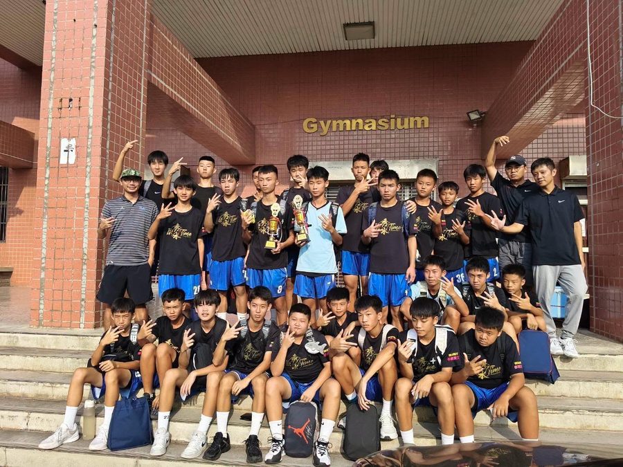 秀水國中籃球隊在體育館前的階梯上合照，手捧獎盃 The Hsiushui basketball team on the steps in front of a gymnasium, holding up their trophies