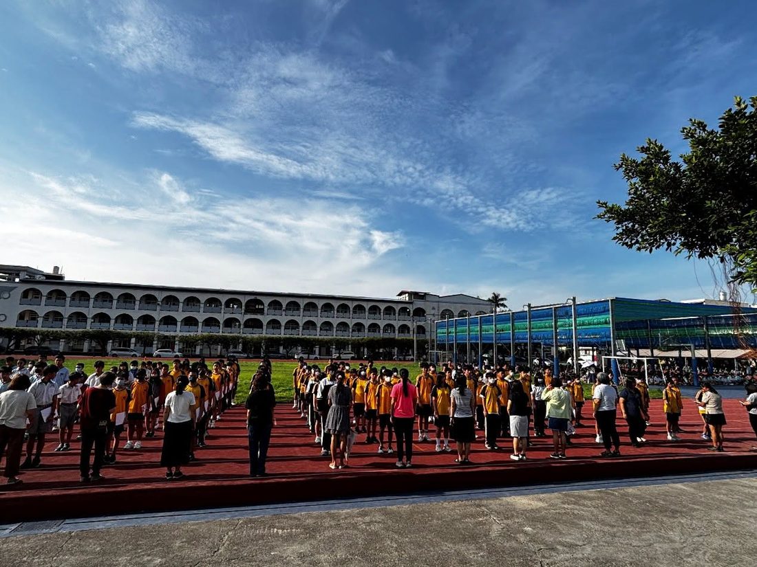 藍天下，秀水國中師生在紅色跑道上排隊集合 Hsiushui students and teachers lined up on the red running track under a blue sky