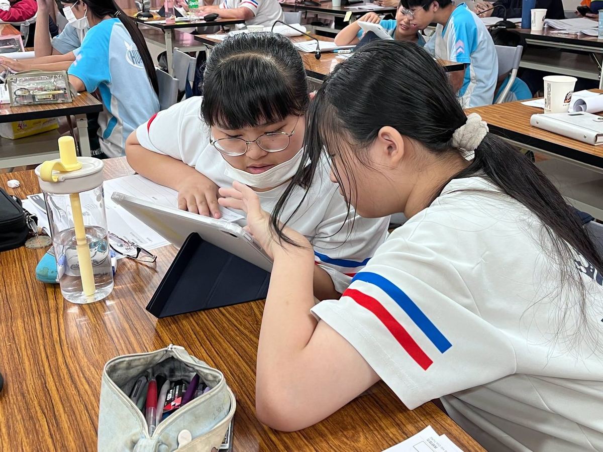 A teacher guiding students through an interactive smart touch-screen TV lesson 老師帶領學生使用智慧觸控電視進行互動教學