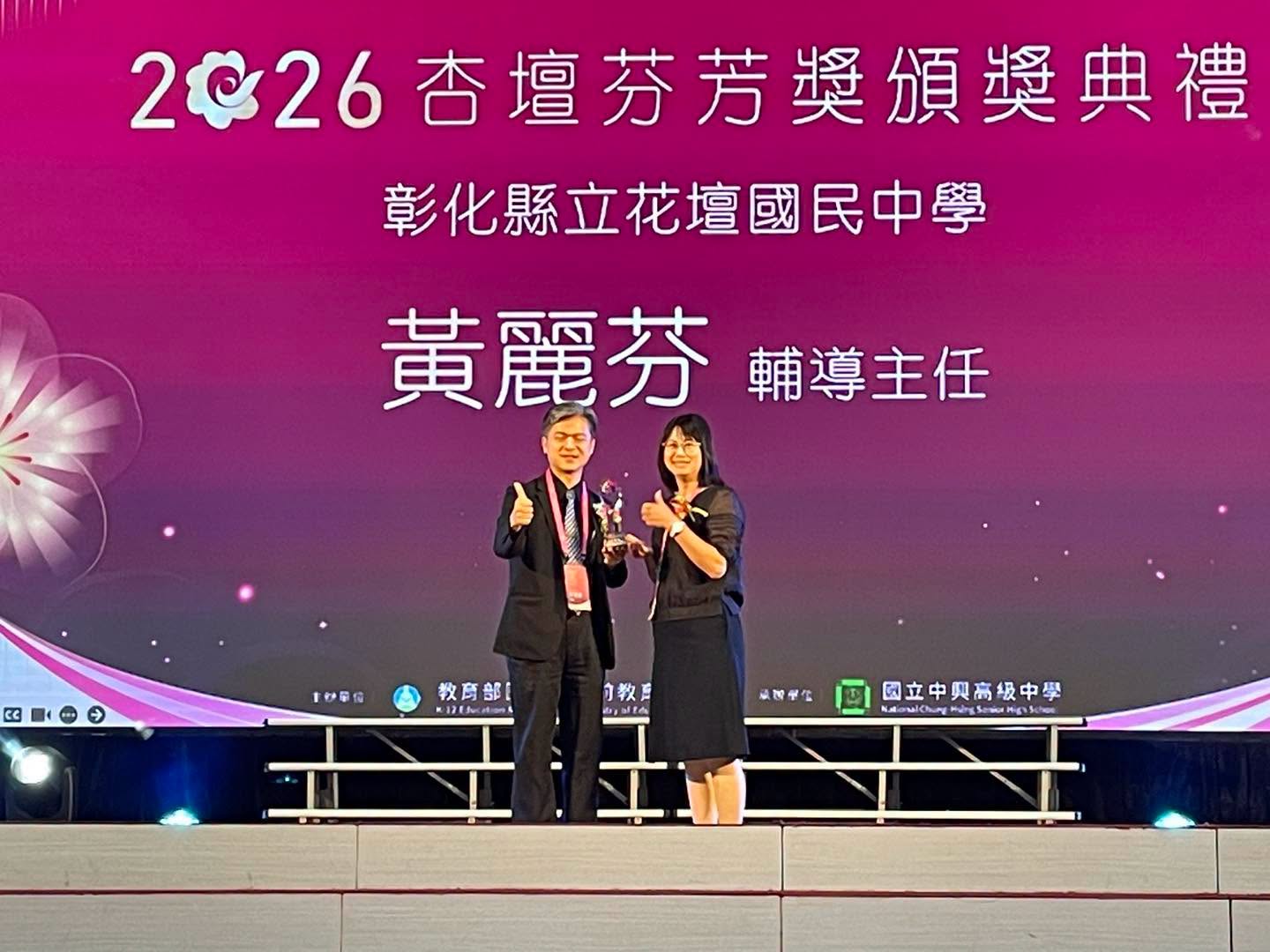 Huatan Junior High counseling director Huang Li-fen receiving the 2026 Education Award trophy on stage 花壇國中輔導主任黃麗芬於2026杏壇芬芳獎頒獎典禮舞台上接受獎座