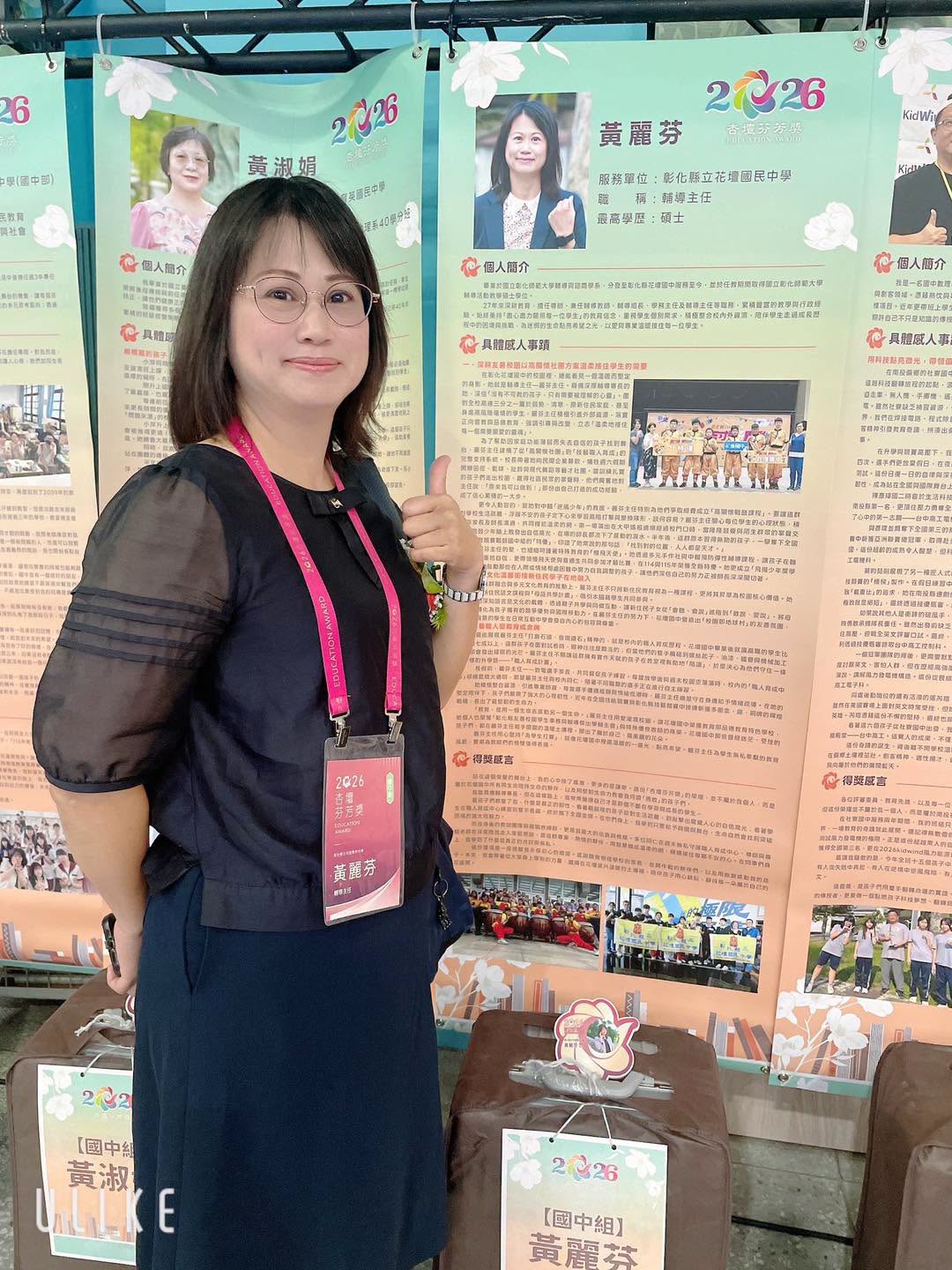 Huang Li-fen standing beside her Education Award display board in the junior high category 黃麗芬主任於杏壇芬芳獎國中組個人事蹟看板前合影