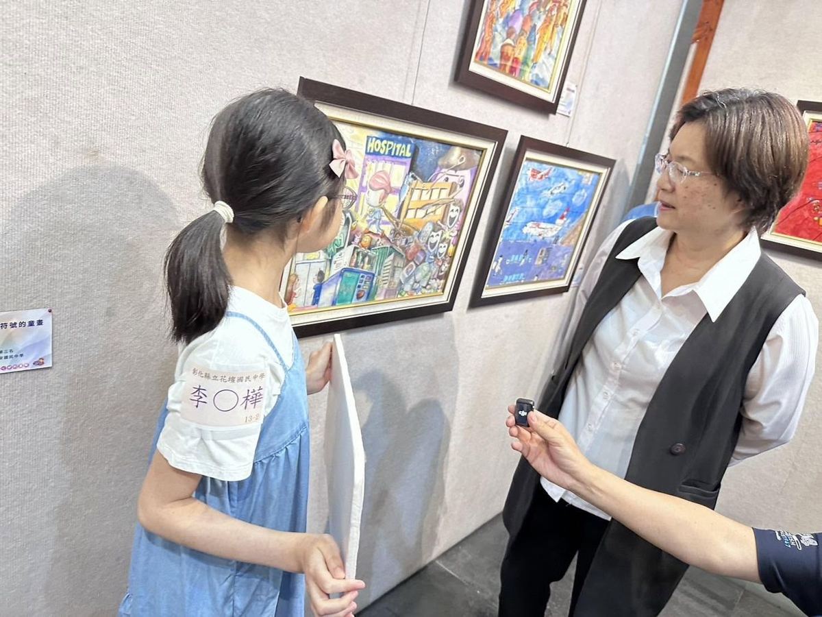 Li Pei-hua speaking with a guest beside her exhibited artwork 李佩樺同學於畫作前與來賓交談