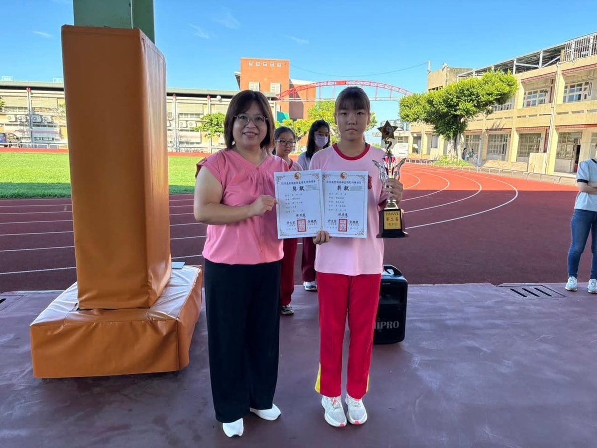 Huatan martial arts coach and student holding certificates and a trophy on the school track 花壇國中武術隊教練與選手手持獎狀與獎盃
