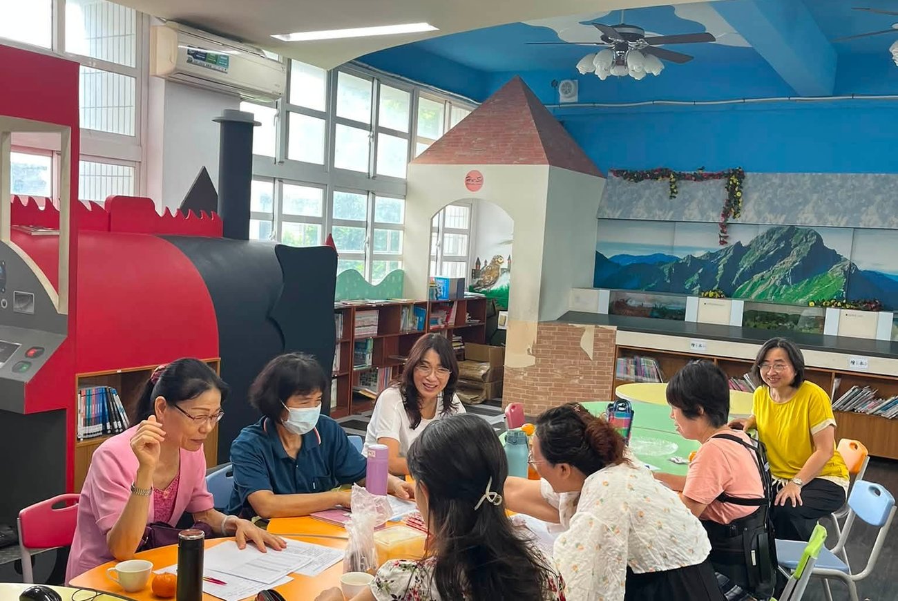 湖西國小生命教育志工團隊在圖書室火車造型閱讀角旁開會備課