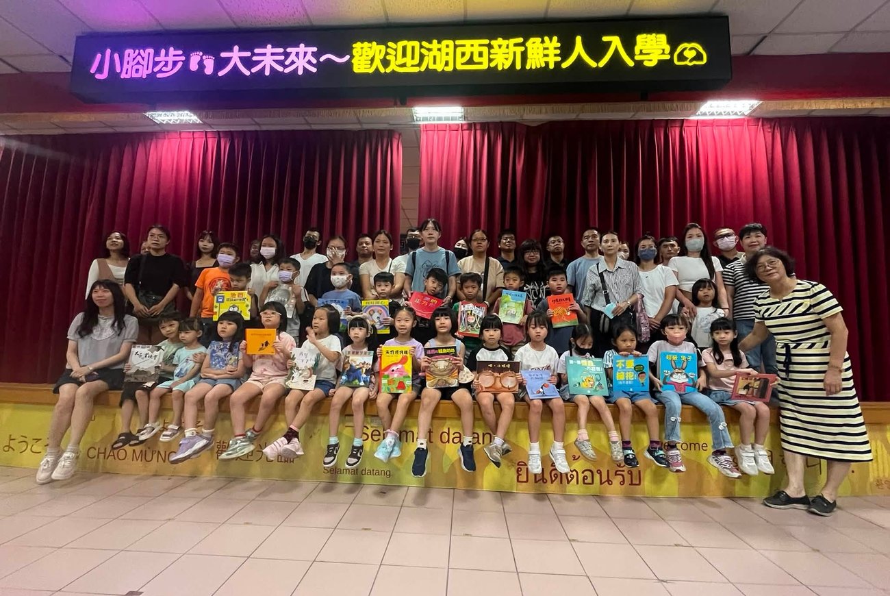 湖西國小新生歡迎會,新生與家長於舞台上手持繪本合影